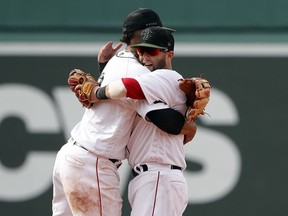 Boston Red Sox second baseman Dustin Pedroia. right, gets a hug from shortstop Xander Bogaerts after their 8-6 win over the Atlanta Braves in a baseball game at Fenway Park in Boston Saturday, May 26, 2018.