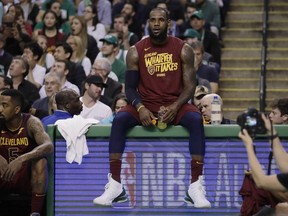 Cleveland Cavaliers forward LeBron James sits on the scorer's table during a timeout in the first half in Game 2 of the team's NBA basketball Eastern Conference finals against the Boston Celtics, Tuesday, May 15, 2018, in Boston. At left is teammate JR Smith.