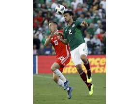 Mexico's Oswaldo Alanis, right, heads the ball away from Wales' Aaron Ramsey during the first half of a soccer match, Monday, May 28, 2018, in Pasadena, Calif.