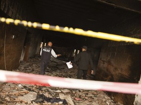 Two police officers investigate the building of Libya's high national elections commission in Tripoli after a suicide bombing Wednesday, May 2, 2018.