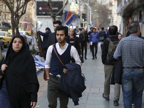 In this Sunday, March 11, 2018, photo, Amir Ali Najafi, center, a transgender man, walks on a sidewalk in downtown Tehran, Iran. Transgender men and women can face harassment in Iran, despite a religious order acknowledging them. Though it may come as a surprise to those abroad, Iran's founding ayatollah issued a religious decree or fatwa for followers to respect transgender people.