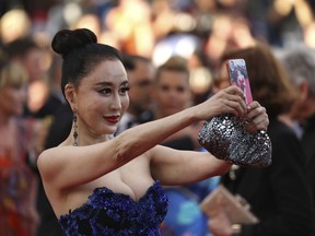 A guest takes a selfie photograph upon arrival at the opening ceremony of the 71st international film festival, Cannes, southern France, Tuesday, May 8, 2018.