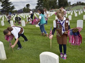 Girl Scouts place flags at the Los Angeles National Cemetery in Los Angeles on Saturday, May 26, 2018. More than 6,000 Scouts, with the support of local community members, placed 88,000 American flags on graves throughout the cemetery to honor fallen service members in anticipation of Memorial Day.