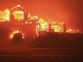 FILE - In this Oct. 9, 2017, file photo, a home burns in Fountaingrove in Santa Rosa, Calif. Police body-camera footage from 2017's wildfires in California's wine country shows officers running door-to-door urging people to flee and rescuing elderly residents of a retirement community as flames bear down. Video obtained by the San Jose Mercury News is from the point-of-view of police in Santa Rosa, as they sprint through swirling smoke amid the firestorm.