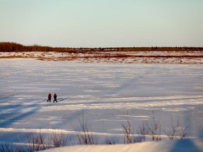 Two people walk across the frozen Severn River alongside Fort Severn, Ont., near Hudson Bay on Friday, April 27, 2018.