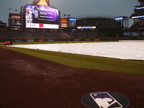 Rain falls on the covered field as a storm sweeps over Coors Field to delay a baseball game between the San Francisco Giants and the Colorado Rockies, Monday, May 28, 2018, in Denver.