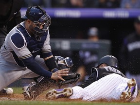 Milwaukee Brewers catcher Manny Pina, left, tries to field the throw as Colorado Rockies' Gerardo Parra scores on a double hit by Ian Desmond in the second inning of a baseball game Friday, May 11, 2018.