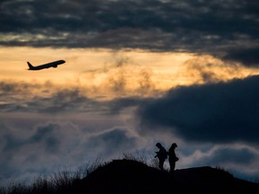 An Air Canada plane takes off as Andrew Yang, left, and Kevin Jiang take photographs of planes taking off and landing at Vancouver International Airport at sunset, in Richmond, B.C., on Sunday, December 31, 2017.