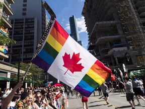 A man holds a flag on a hockey stick during the Pride parade in Toronto on June 25, 2017. Police will march in this year's Edmonton Pride festival, but not in uniforms.The Edmonton Pride Festival Society says they restricted enforcement vehicles, lights and sirens in the 2017 parade after a similar move was made in Toronto.THE CANADIAN PRESS/Mark Blinch