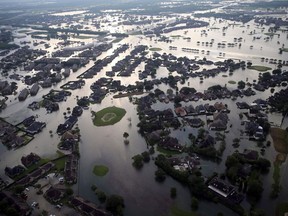 In this Aug. 31, 2017, file photo, floodwaters from Tropical Storm Harvey surround homes in Port Arthur, Texas.