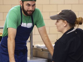 FILE - In this Sept. 23, 2016 file photo, chef Daniel Giusti, left, chats with chef April Kindt between lunch waves at Bennie Dover Jackson Middle School in New London, Conn. What kind of meal can you buy for $1.25? Guisti will host ten chefs on Saturday, June 2, 2018, competing at the middle school to make the best possible school lunch on that budget while meeting nutritional standards required by public schools.