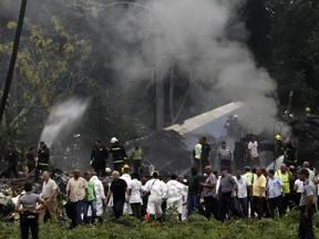 Cuba's President Miguel Diaz-Canel, third from left, walks away from the site where a Boeing 737 plummeted into a yuca field with more than 100 passengers on board, in Havana, Cuba, Friday, May 18, 2018. The Cuban airliner crashed just after takeoff from Havana's international airport on Friday.