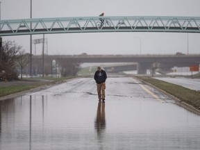 A pedestrian walks along a closed street in downtown Fredericton, N.B. as floodwaters from the St. John River remain level on Monday, April 30, 2018.