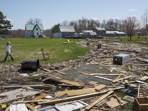 Michelle Cain looks for belongings in debris from homes and cottages destroyed by the floodwater from the Saint John River in Robertson's Point, N.B., on Sunday, May 13, 2018.