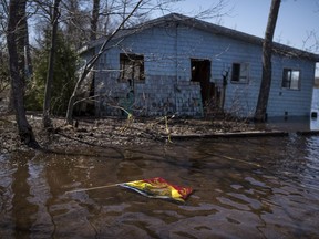 A New Brunswick flag floats in front of a cottage destroyed by flooding from the Saint John River in Waterborough, N.B., on Sunday, May 13, 2018.