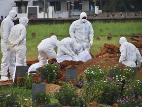In this Thursday, May 24, 2018, photo, paramedics wear protective suits as a precautionary measure against the Nipah virus as they bury Valachekutti Mosa's body, died of the same virus, in Kozhikode, in the southern Indian state of Kerala. More than 10 people have died of Nipah since an outbreak began earlier this month in Kerala, health officials say. There is no vaccine for the virus, which can cause raging fevers, convulsions and vomiting, and kills up to 75 percent of people who come down with it.
