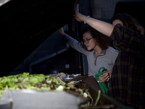 Emily Kirbyson, left, and Rebecca Rogerson look through a garbage bin behind a grocery story for produce and other edibles near or just past their expiry date in an effort to create a cookbook on dumpster diving for their thesis work at the University of Victoria.