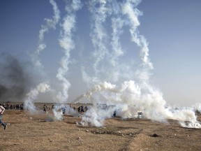 FILE - In this Tuesday, May 15, 2018 file photo, Palestinian protesters run from teargas fired by Israeli troops at the Gaza Strip's border with Israel. The aftershocks of the U.S. Embassy move to Jerusalem and bloodshed on the Gaza border are shaking up the region, including the relationship between Palestinian President Mahmoud Abbas and former his negotiating partners, Israel and the U.S. Seething over a perceived U.S. betrayal on Jerusalem, Abbas is preparing to pursue what has been called his "doomsday weapon," a war crimes complaint against Israel at the International Criminal Court.