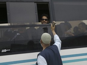 In this Tuesday, May 22, 2018 photo, Hamed al-Shaer, 34, rides a bus while man offers to exchange money before crossing the border to the Egyptian side of Rafah crossing with Egypt, in Khan Younis, in the Gaza Strip. Egypt has opened Rafah for the duration of the Muslim fasting month of Ramadan, temporarily easing a border blockade of Gaza it has enforced, along with Israel, for the past 11 years. But thousands of people hoping to travel are on a waiting list, a backlog accumulated over long periods of Rafah closures, and Egyptian border officials are processing them at an excruciatingly slow pace.