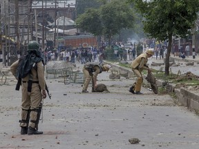 Indian policemen remove rocks, set up as barricade by Kashmiri protesters, near the site of a gun battle in Srinagar, Indian controlled Kashmir, Saturday, May 5, 2018. Fierce clashes erupted when residents in solidarity with the rebels tried to march to the gunbattle site. A vehicle belonging to Indian troops ran over and killed a man as protesters clashed with government forces, residents said.