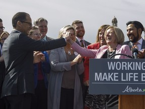 Alberta Premier Rachel Notley high fives Finance Minister Joe Ceci at a press conference to speak about the Kinder Morgan pipeline project, in Edmonton on Tuesday, May 29, 2018.THE CANADIAN PRESS/Jason Franson