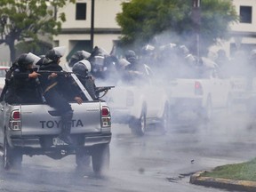 Police in riot gear riding on the back of pick-up trucks fire their shotguns towards university students taking part in a protest against Nicaragua's President Daniel Ortega in Managua, Nicaragua, Monday, May 28, 2018. Violence returned to Nicaragua when riot police confronted protesters and students seized a university.