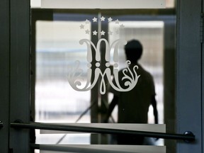 This April 2, 2018 photo shows a large cursive M with 12 stars, a symbol that is identified with the Marist Brothers, adorning a glass door, backdropped by the silhouette of a student walking nearby, at the Alonso de Ercilla Institute in Santiago, Chile. The Marist Brothers congregation has revealed that at least 14 minors were abused from the 1970s until 2008 by a brother who worked at two of the order's schools.
