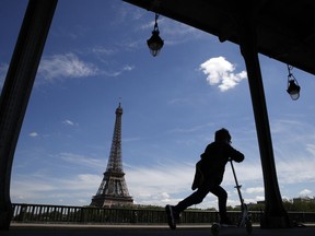 A boy rides his scooter on the Bir Hakeim bridge as the Eiffel Tower is seen background in Paris, Wednesday, May 2, 2018.