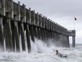 A surfer makes his way out into the water as a subtropical approaches on Monday, May 28, 2018, in Pensacola, Fla. The storm gained the early jump on the 2018 hurricane season as it headed toward anticipated landfall sometime Monday on the northern Gulf Coast, where white sandy beaches emptied of their usual Memorial Day crowds.