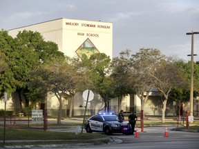 FILE - In this Feb. 23, 2018 file photo, police watch the entrance of a parking lot at Marjory Stoneman Douglas High School in Parkland, Fla. where teachers and administrators returned for the first time since the Valentine's Day shooting that killed several people. Marjory Stoneman Douglas High School drama teacher Melody Herzfeld will be the recipient of the Tony Award for Excellence in Theatre Education. Herzfeld will be presented with the award onstage June 10 at the Tony telecast.