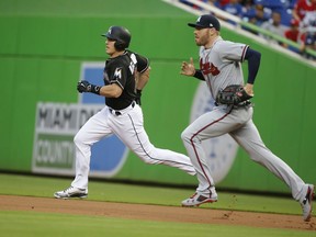 Atlanta Braves first baseman Freddie Freeman, right, runs alongside Miami Marlins' J.T. Realmuto as Realmuto heads to second base for a double during the first inning of a baseball game, Friday, May 11, 2018, in Miami.