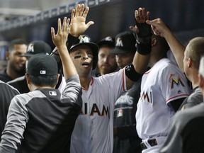 Miami Marlins' Martin Prado, center, is congratulated by teammates after scoring on a single by Brian Anderson during the first inning of a baseball game against the Los Angeles Dodgers, Wednesday, May 16, 2018, in Miami.