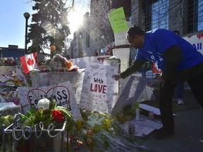 A man places a placard before a vigil remembering the victims of a deadly van attack, at Mel Lastman Square in Toronto on Sunday, April 29, 2018.