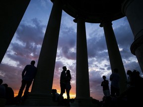 In this May 29, 2018 photo strollers watch the sunset at the Monopteros in the English Garden in Munich, southern Germany.