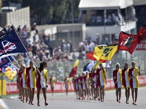 FILE - In this Aug. 23, 2015 file photo grid girls carry flags prior the Belgium Formula One Grand Prix at the Spa-Francorchamps circuit, Belgium. Women will make a return of sorts to the Formula One grid at this weekend's Monaco Grand Prix, although not in the traditional "grid girls" role now outlawed.
