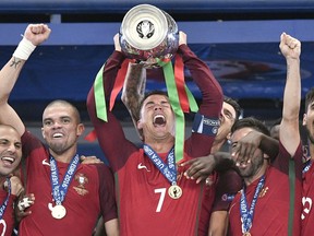 FILE - In this Sunday, July 10, 2016 file photo, Portugal's Cristiano Ronaldo holds the trophy at the end of the Euro 2016 final soccer match between Portugal and France at the Stade de France in Saint-Denis, north of Paris. Cristiano Ronaldo and Lionel Messi put up impressive numbers, in life and on the field, going into a fourth World Cup for each. So much has happened for football's standout stars since the 2014 tournament left both still lacking the game's most coveted prize.