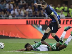 Inter Milan's Mauro Icardi, top, and Sassuolo's Claud Adjapong go for the ball during the Serie A soccer match between Inter Milan and Sassuolo at the San Siro stadium in Milan, Italy, Saturday, May 12, 2018.