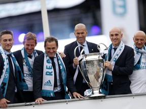 Real Madrid head coach Zinedine Zidane, third right, and his assistants pose with the trophy in Cibeles Square in Madrid, Spain, Sunday, May 27, 2018, to celebrate winning the Champions League final soccer match against Liverpool.