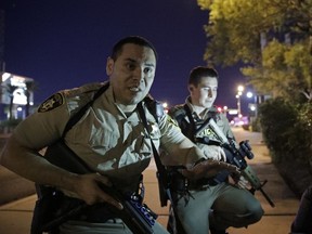 FILE - In this Oct. 1, 2017, file photo, police officers advise people to take cover near the scene of a shooting near the Mandalay Bay resort and casino on the Las Vegas Strip in Las Vegas. Police in Las Vegas promised to release dispatch logs and additional officer reports on Wednesday, May 23, 2018, providing more witness accounts of the chaos, carnage and compassion during the deadliest mass shooting in modern U.S. history. The scheduled release of documents follows a court order in a public records lawsuit by The Associated Press and other media organizations seeking information about the Oct. 1 shooting.