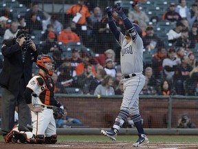 San Diego Padres' Christian Villanueva, right, celebrates after hitting a home run, in front of San Francisco Giants catcher Buster Posey, center, and umpire Hunter Wendelstedt during the first inning of a baseball game in San Francisco, Tuesday, May 1, 2018.