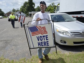 In preparation for election day Tuesday, Raymond Sharp and other workers carry signs into the polling location at Asbury United Methodist Church Monday, May 21, 2018 in Augusta, Ga.