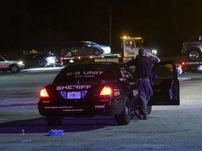 A Clayton County Sheriff's Deputy stands watch over a parking lot at Mt. Zion High School as three cars are towed away as part of an investigation into a fatal shooting Friday, May 18, 2018, in Jonesboro, Ga. One person was killed and another wounded when an argument led to a shooting outside a high school graduation ceremony Friday night in metro Atlanta, police said. The incident happened as people headed to their cars, Clayton County schools' safety chief Thomas Trawick said.