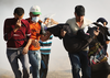 Palestinian protesters run through tear gas carrying an injured woman at the border fence with Israel on May 15, 2018 in Gaza.