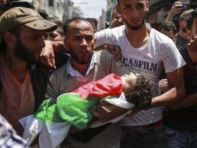 The father of Layla Ghandour, an 8-month-old overcome by tear gas, carries her body during her funeral in Gaza City, May 15, 2018.