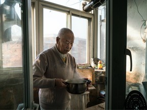 Han holds part of his breakfast, a pot of boiled soy milk, in his kitchen.