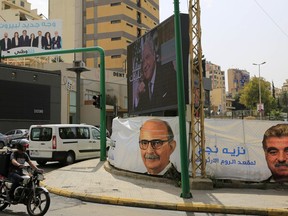 In this Tuesday, May 1, 2018 photo, a poster of the Kulna Watani list, left top, and posters for parliamentary elections include a portrait of former Lebanese Prime Minister Rafic Hariri, right adorn a street in Beirut, Lebanon, Tuesday, May 1, 2018. In Lebanon's first national elections in nine years, candidates once considered an afterthought in the polls, a mix of civic activists, businessmen, journalists and engineers are forming the broadest coalition yet to challenge the traditional parties and warlords that ruled the country since the country's civil war ended in 1990.
