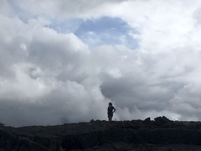 Tommie Joy Higgins of Hawaiian Paradise Park, Hawaii, stands on an old lava flow from 2014 as she watches plumes of volcanic gases rise from nearby active lava fissures on Tuesday, May 15, 2018 in Pahoa, Hawaii.