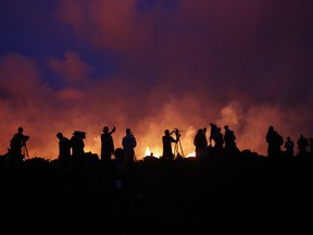 In this Thursday, May 24, 2018 photo, residents and members of the media are silhouetted as active lava fissures near what is now the end of Leilani Street continue to spew forth lava at Leilani Estates near Pahoa, Hawaii.