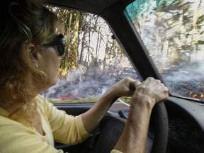 In this Sunday, May 6, 2018, photo, Leilani Estates resident Lucina Aquilina drives near lava on Luana Street in the Leilani Estates subdivision, in Pahoa, Hawaii. Hawaii's Kilauea volcano has destroyed homes and spewed lava hundreds of feet into the air, leaving evacuated residents unsure how long they might be displaced.