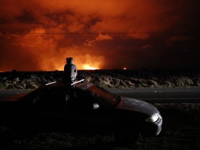 Brittany Kimball watches as lava erupts from from a fissure near Pahoa, Hawaii, Saturday, May 19, 2018. Two fissures that opened up in a rural Hawaii community have merged to produce faster and more fluid lava. Scientists say the characteristics of lava oozing from fissures in the ground has changed significantly as new magma mixes with decades-old stored lava.